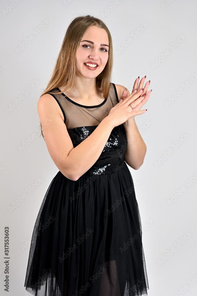 Universal concept vertical woman portrait on a white background. A photo of a pretty smiling girl with long hair and excellent make-up in a black dress is standing in various poses in the studio. Universal concept vertical woman portrait on a white background. A photo of a pretty smiling girl with long hair and excellent make-up in a black dress is standing in various poses in the studio.