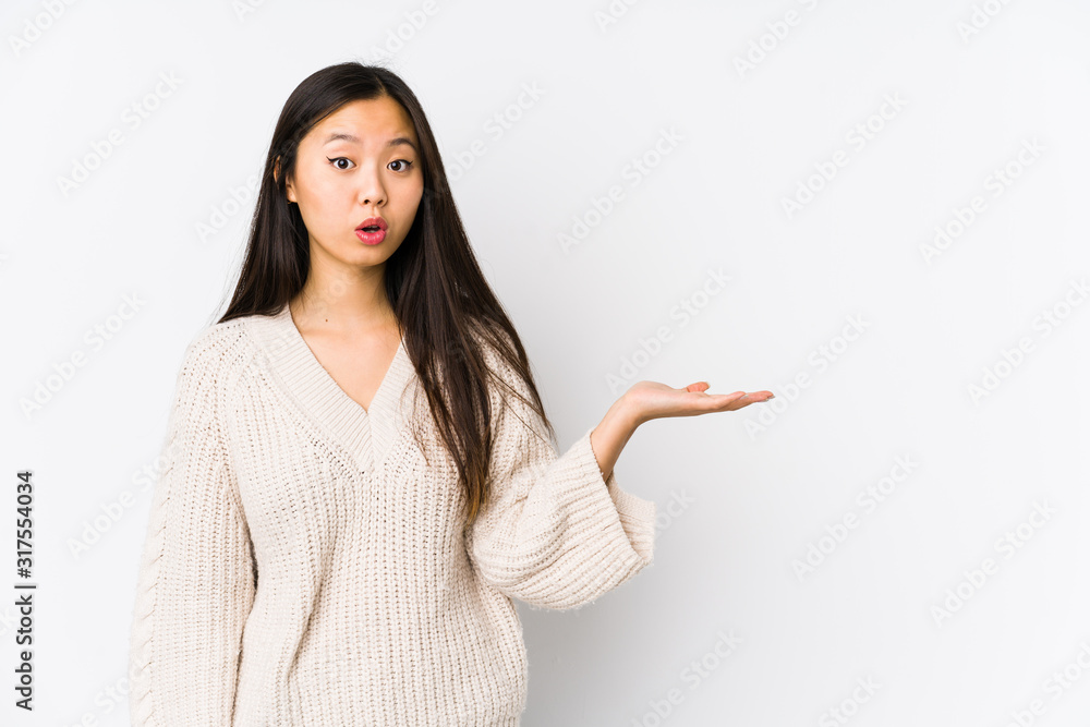 Young chinese woman isolated impressed holding copy space on palm. Young chinese woman isolated impressed holding copy space on palm.