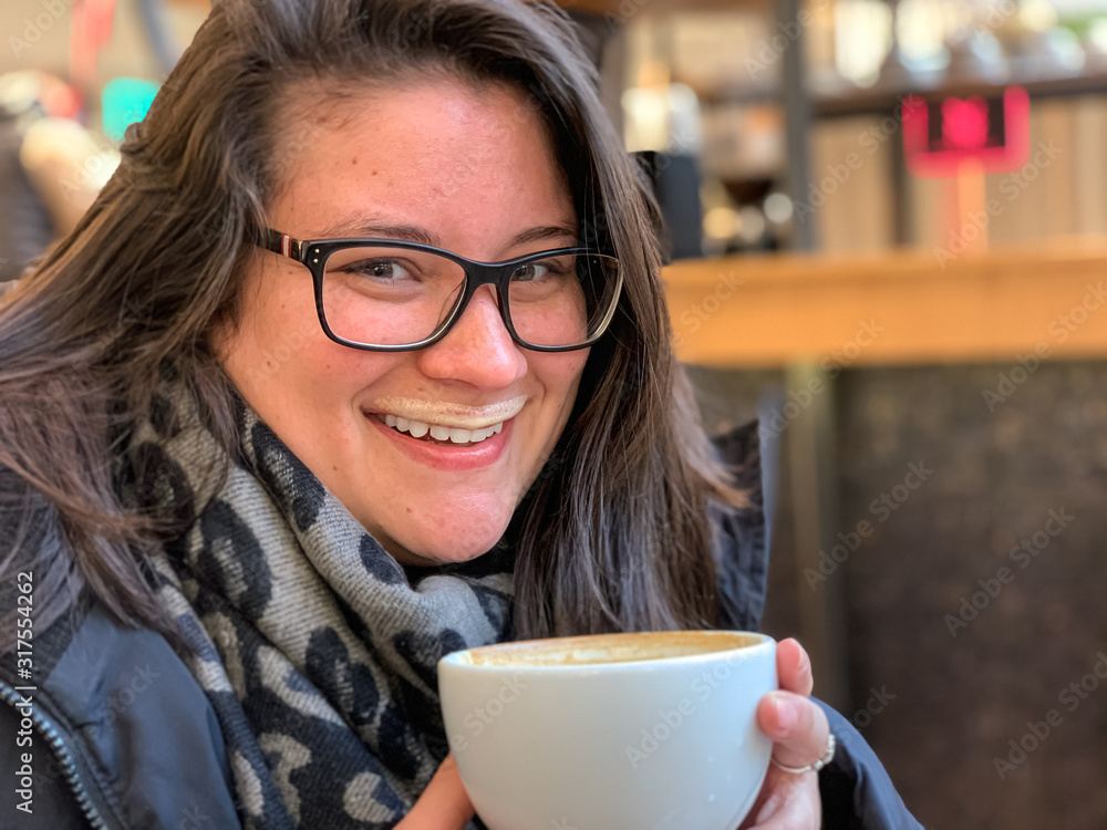 Young lady is drinking coffee happily, she is smiling to the camera Young lady is drinking coffee happily, she is smiling to the camera