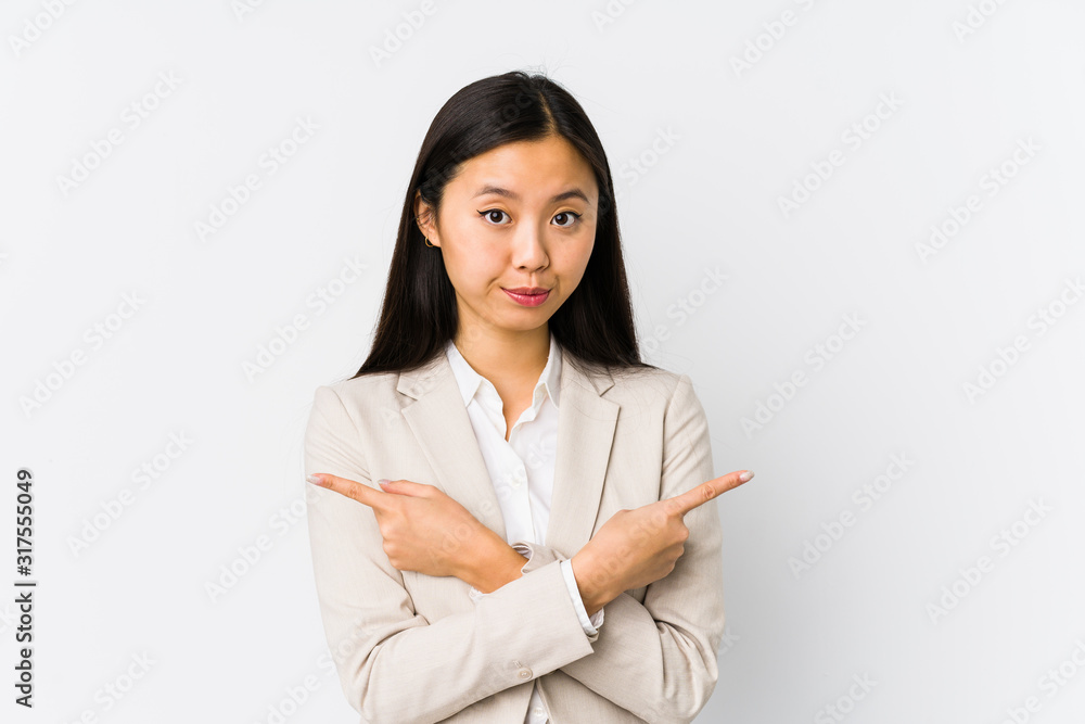 Young chinese business woman isolated points sideways, is trying to choose between two options. Young chinese business woman isolated points sideways, is trying to choose between two options.