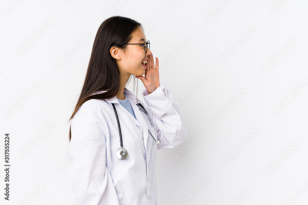 Young doctor chinese woman isolated shouting and holding palm near opened mouth. Young doctor chinese woman isolated shouting and holding palm near opened mouth.