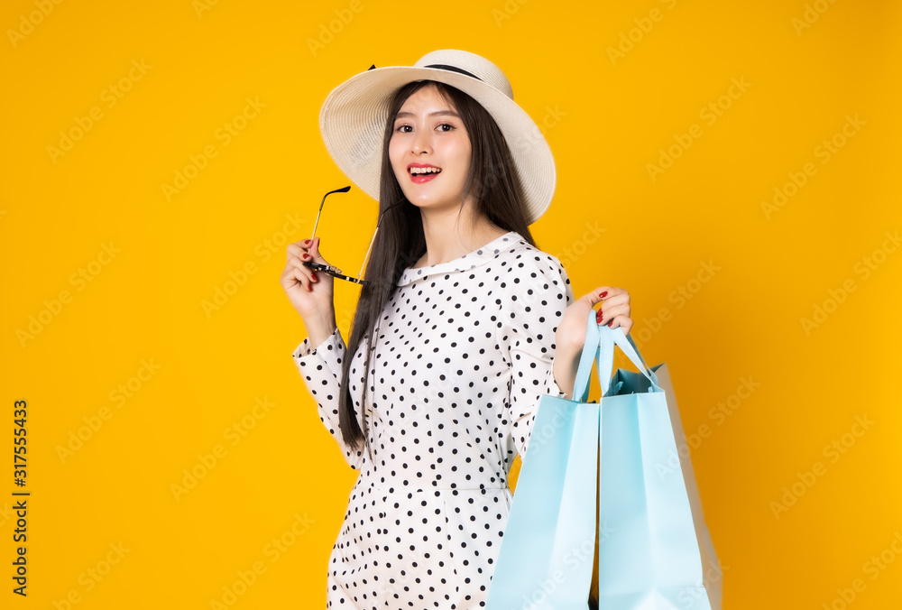 Asian woman in summer casual clothes.She smiling and  happy shopping bags. she  lovely attractive shine on  yellow background.Summer Surprise Sale  concept.
