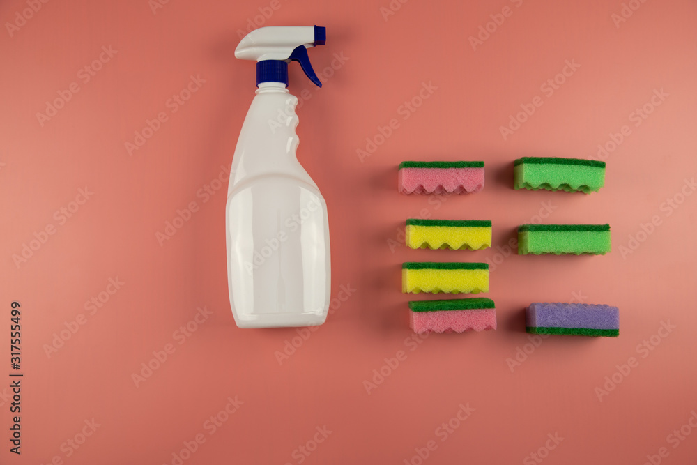 white spray bottle and multi-colored washcloths on a pink background white spray bottle and multi-colored washcloths on a pink background