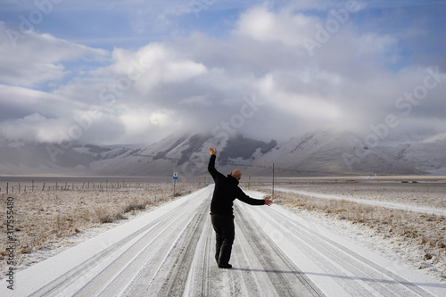 Happy man dancing in an empty mountain road on a winter day. Castelluccio, Norcia, Umbria, Italia