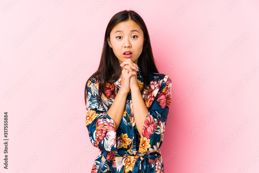 Young chinese woman wearing a kimono pajama isolated praying for luck, amazed and opening mouth looking to front. Young chinese woman wearing a kimono pajama isolated praying for luck, amazed and opening mouth looking to front.