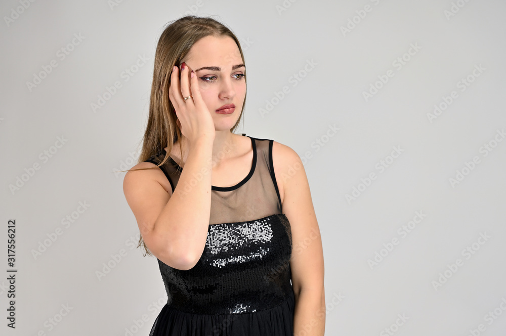 Fototapeta premium Universal concept horizontal portrait of a woman on a white background. A photo of a pretty smiling girl with long hair and excellent make-up in a black dress stands in different poses.