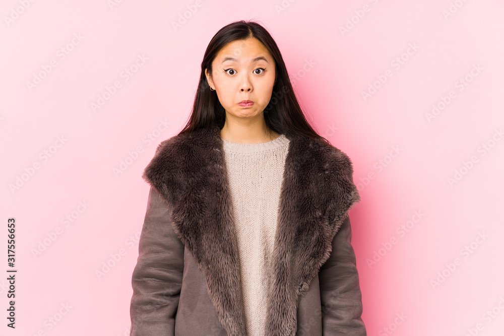 Young chinese woman wearing a coat isolated shrugs shoulders and open eyes confused. Young chinese woman wearing a coat isolated shrugs shoulders and open eyes confused.