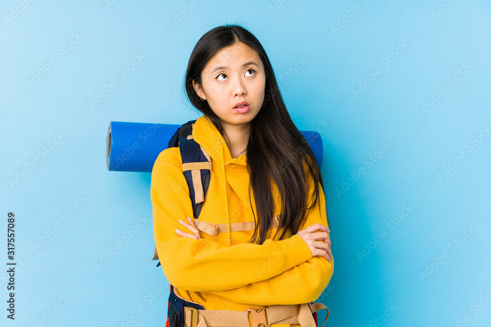 Young chinese backpacker woman isolated tired of a repetitive task. Young chinese backpacker woman isolated tired of a repetitive task.