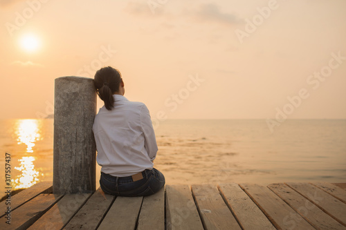 Fotografie, Tablou Beautiful woman sitting Alone with loneliness At the wooden bridge by the sea Du