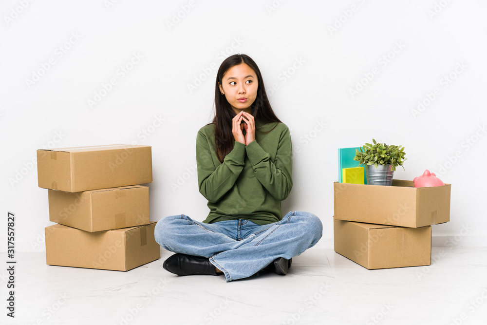 Young chinese woman moving to a new home making up plan in mind, setting up an idea. Young chinese woman moving to a new home making up plan in mind, setting up an idea.