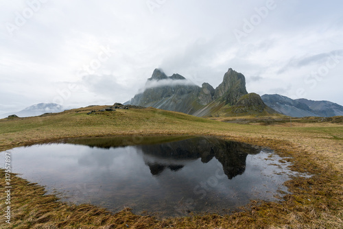 View over Eystrahorn mountain chain who reflects in little pond. Foggy and overcast weather. Hvalnes peninsula next to the national ring road number one. photo