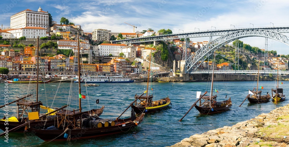 Portugal, city landscape Porto, a group of yellow wooden boats with wine port barrels on Douro river, panoramic view of the old town Porto,  The Eiffel Bridge view, Ponte Dom Luis, stone embankment