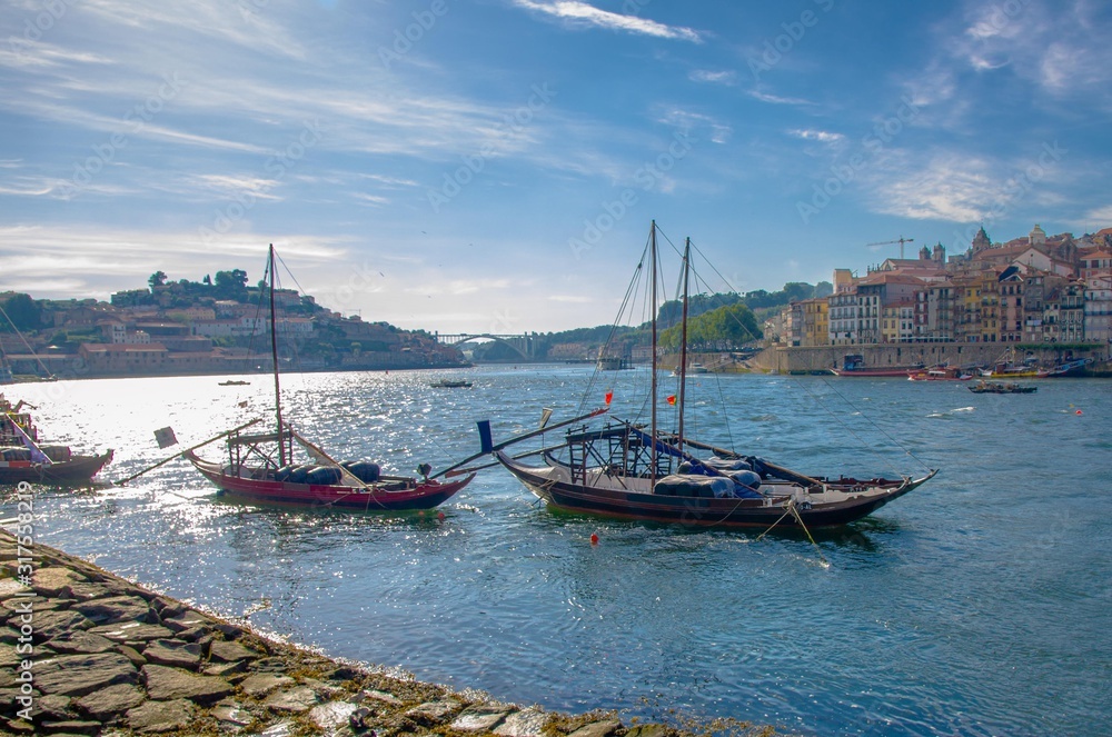 Portugal,  Porto, a group of wooden boats with wine port barrels close up on Douro, Porto by river,  Porto in summer, riverbed Douro, Porto city alone the river Douro, blue sky with white high clouds