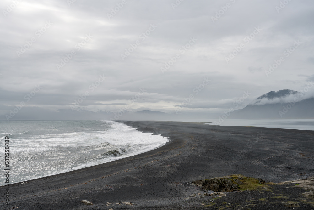 View over Atlantic ocean and Hvalnes beach next to the Ring road in Iceland. Tourists walks on the beach. View over Atlantic ocean and Hvalnes beach next to the Ring road in Iceland. Tourists walks on the beach.