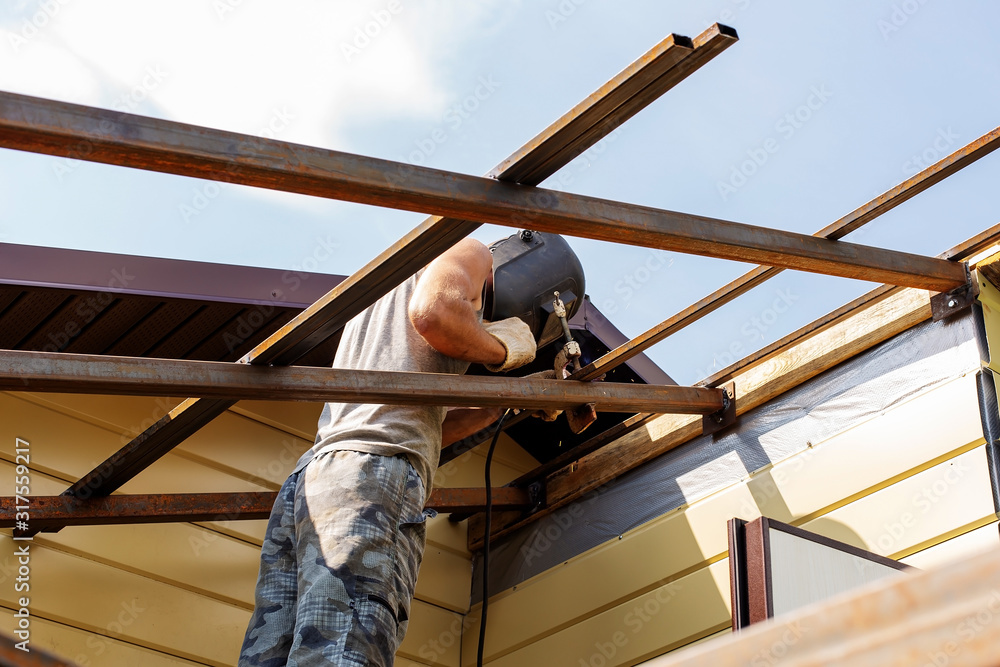 A man builds a wooden house, a welder