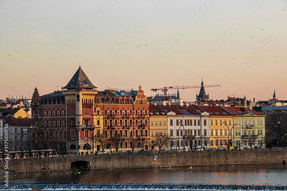 Obraz premium Sunlit old buildings in city Prague with river Vltava