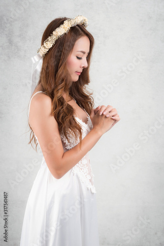 Vintage style portrait beautiful woman wearing a white dress, flower crown on gray soft blurred background.