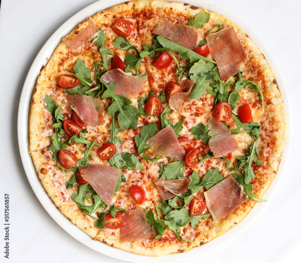 Italian cuisine. Pizza with ham, arugula and tomatoes on a white background. Top view
