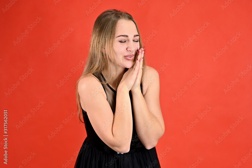 Universal concept horizontal female portrait on a red background. A photo of a pretty smiling girl with long hair and excellent make-up in a black dress stands in different poses. Universal concept horizontal female portrait on a red background. A photo of a pretty smiling girl with long hair and excellent make-up in a black dress stands in different poses.