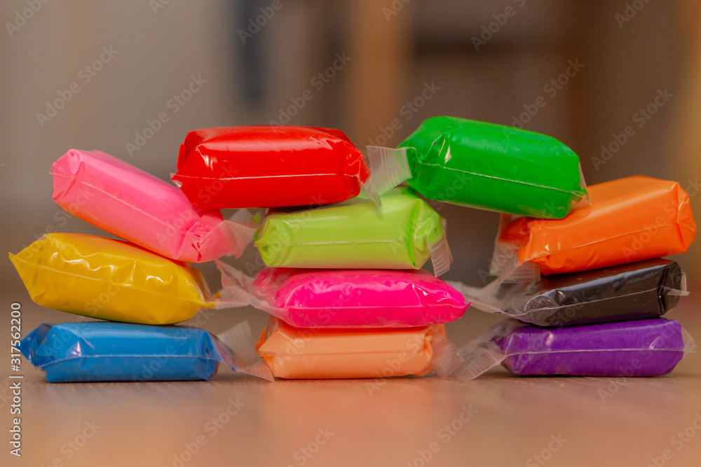 multi-colored plasticine sachets on a wooden surface multi-colored plasticine sachets on a wooden surface