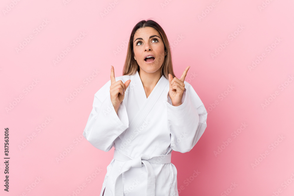 Young karate woman pointing upside with opened mouth. Young karate woman pointing upside with opened mouth.