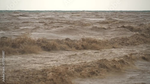 Brown muddy sea waves. Flood waters join reach the sea. Creates strong wave at the mouth of the river. Soil mud is moving towards the sea after rain. An incredibly fast flowing raging river ocean. photo