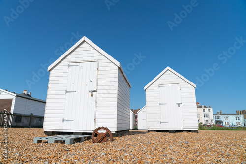 Two white beach sheds on Deal waterfront.