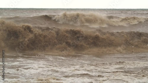 Brown muddy sea waves. Flood waters join reach the sea. Creates strong wave at the mouth of the river. Soil mud is moving towards the sea after rain. An incredibly fast flowing raging river ocean. photo