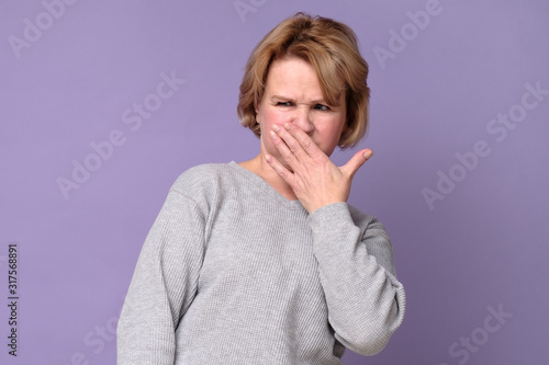 Φωτογραφία Handsome expressive grandmother coering nose from hodor and bad smell from kitchen