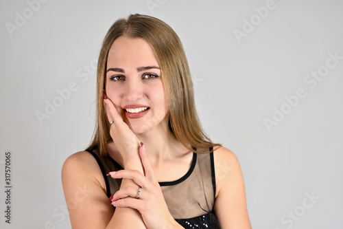 A large photo of a pretty smiling girl with long hair and excellent make-up is standing in different poses. Generic female portrait concept for cosmetics advertising on a white background.