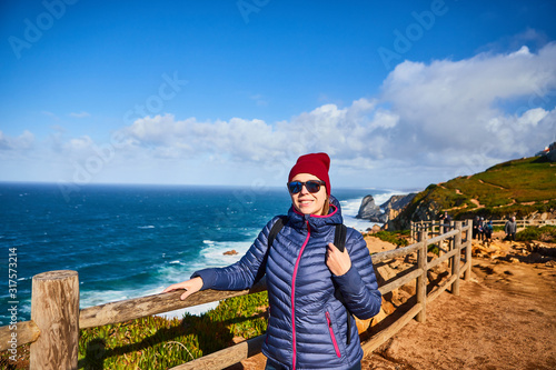 Young woman tourist at Cape Cabo da Roca with view on beautiful landscape, winter trip . Westernmost point of Europe in Portugal