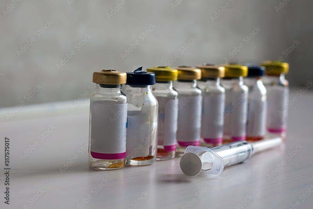 Antibiotic bottles are on a white table with a syringe. Antibiotic bottles are on a white table with a syringe.