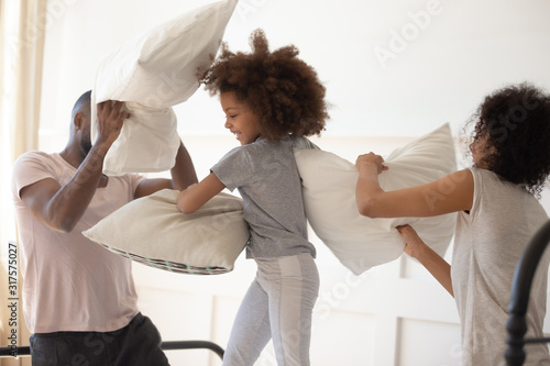 African parents fighting pillows with little daughter