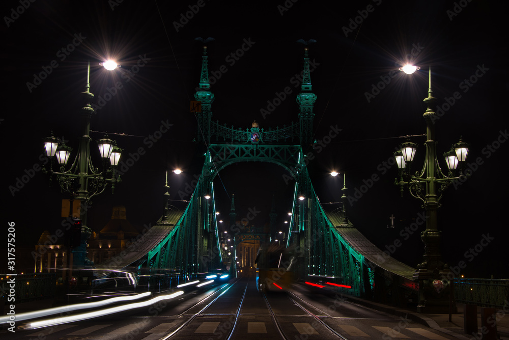 Obraz premium Beautiful Long exposure image of Freedom Bridge in Budapest, Hungary. View of light trails along the road. Night photography.