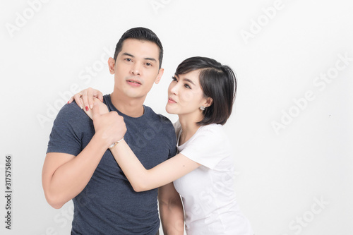Portrait of happy young couple embracing in studio shot on white background.