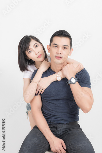 Portrait of happy young couple embracing in studio shot on white background.