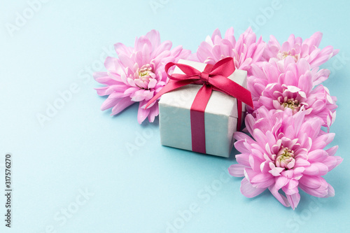 Pink flowers and gift box on blue background. Background for Valentine Day, Mothers Day or Birthday. Space for text. © Eirene Fagus
