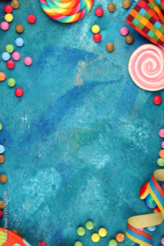 Colorful carnival border over a cool textured background with copy space with party hats, candy, streamers and hearts. Party Carnival decoration