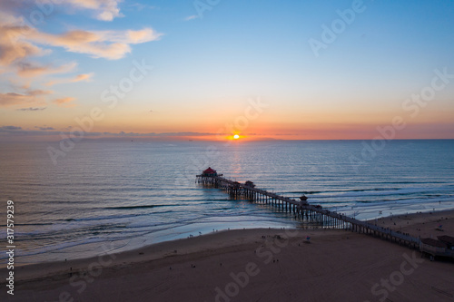 Aerial view of wooden pier in Huntington Beach  Orange County in Southern California at sunset with waves crashing below at sunset.