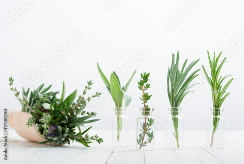 Foto herbal plants in mini bottles and bunch on scoop, white wood table background