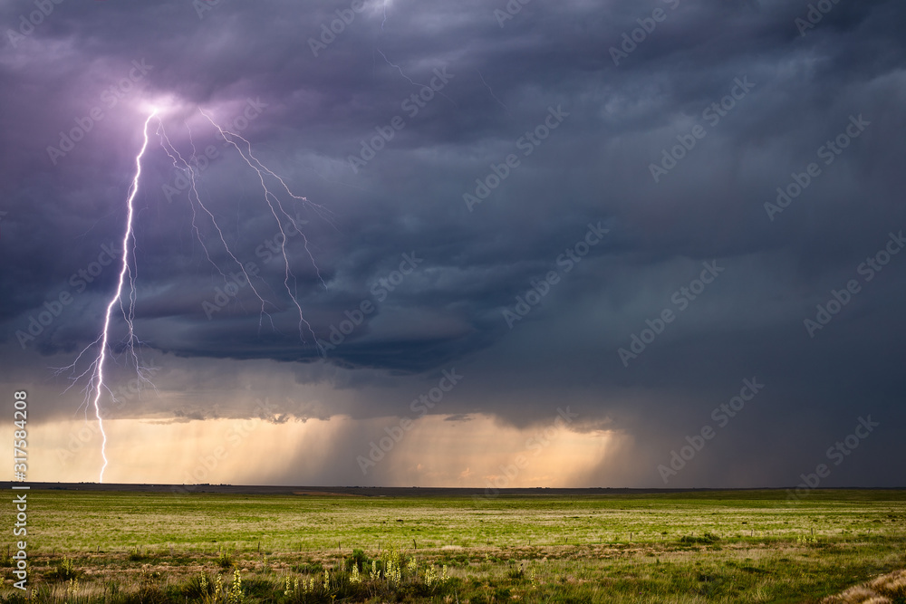 Thunderstorm lightning bolt strike and dark clouds over a field