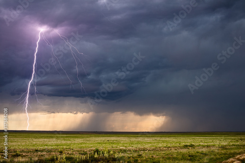 Thunderstorm lightning bolt strike and dark clouds over a field