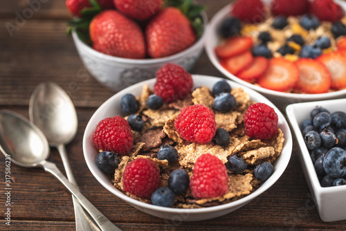 Granola chips with blueberries and raspberries in white bowl.