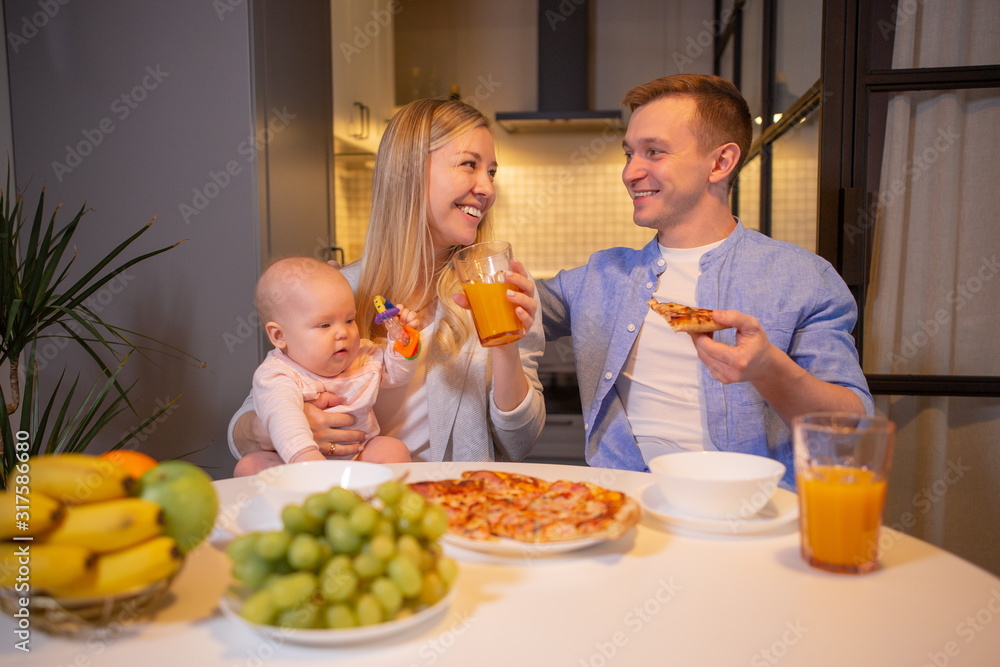 Young family with a baby eating sitting at the table Young family with a baby eating sitting at the table