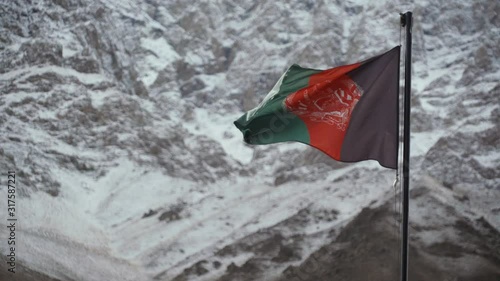 afghanistan flag waving in the wind against the backdrop of snowy mountains