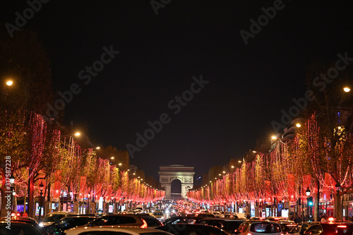 Straßenansicht der Champs Elysee bei Nacht mit roter Beleuchtung und Autos (Frankreich, Paris)