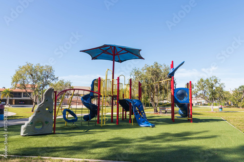 Playground for kids in sunny Florida. South west FL tropical landscape with children’s colorful equipment at a safe park. Bright and cheerful outdoors landscape.