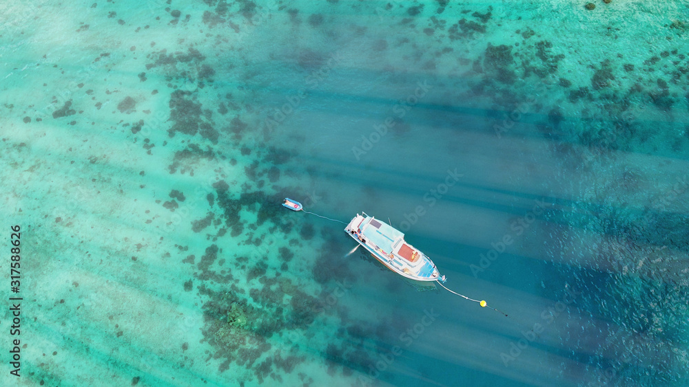 Fototapeta premium Boat anchored on the coral reef, aerial view from drone