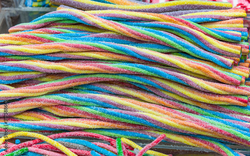 Colorful bright chewy candies covered with sugar. Rainbow ribbon candies. Colorful jelly candies close up as a bright joyful background. Top view. Candy background.