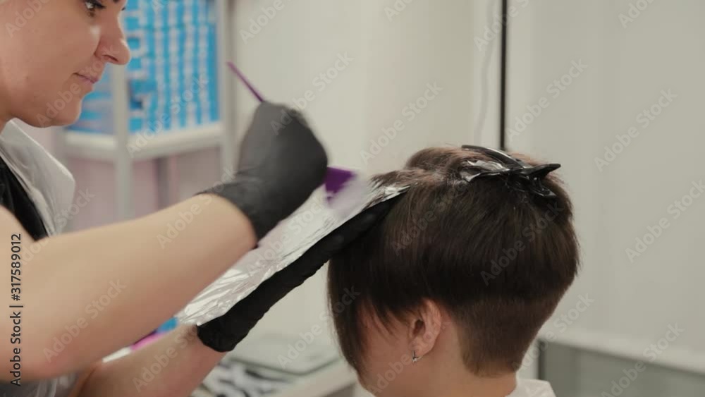 Professional hairdresser woman dyes girl's hair with hair dye on foil. Professional hairdresser woman dyes girl's hair with hair dye on foil.